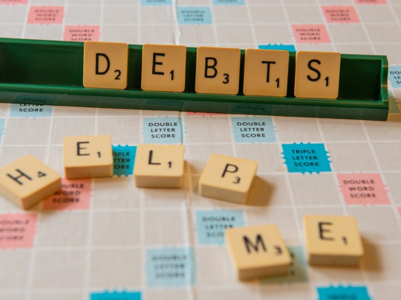 closeup-debts-help-me-written-scramble-board-lights